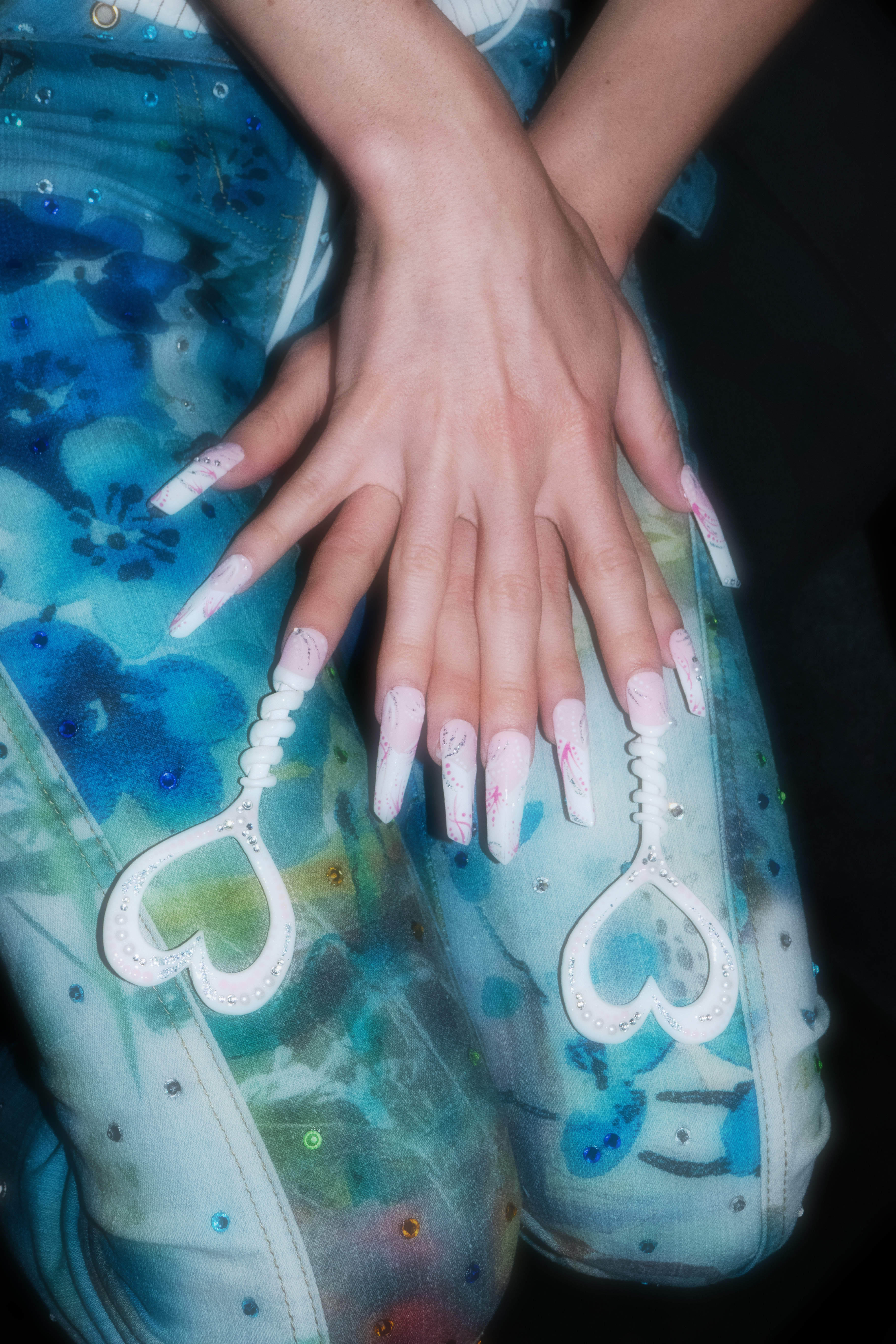 Close up image of Jesse's nails which features rhniestones and 3D printed heart shapes.